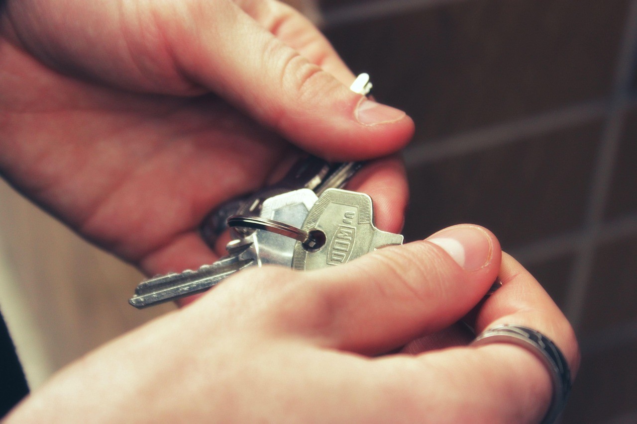 Une main remettant un trousseau de clés de maison à une autre main