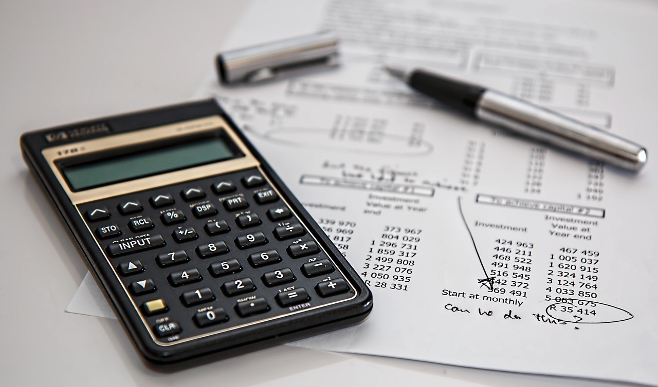 Calculatrice et document financier annoté à la main, symbole de l'analyse manuelle