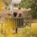 Couple de retraités assis sur un banc dans un jardin, vu de dos