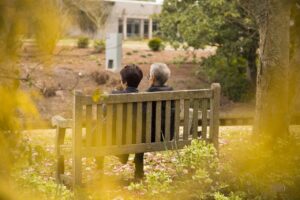 Couple de retraités assis sur un banc dans un jardin, vu de dos
