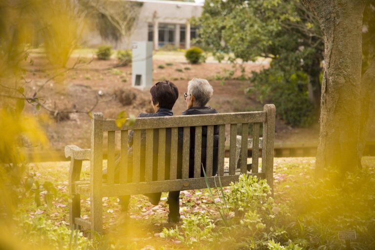 Couple de retraités assis sur un banc dans un jardin, vu de dos